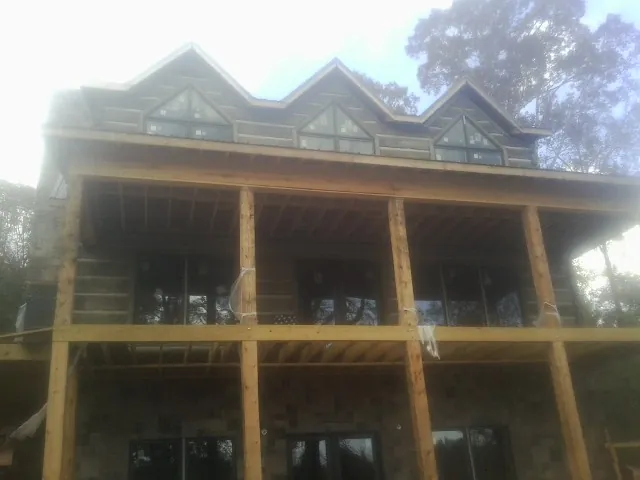 Dormers and porch framing on a large log home under construction — Roof Coating work by our crew in Kennedy