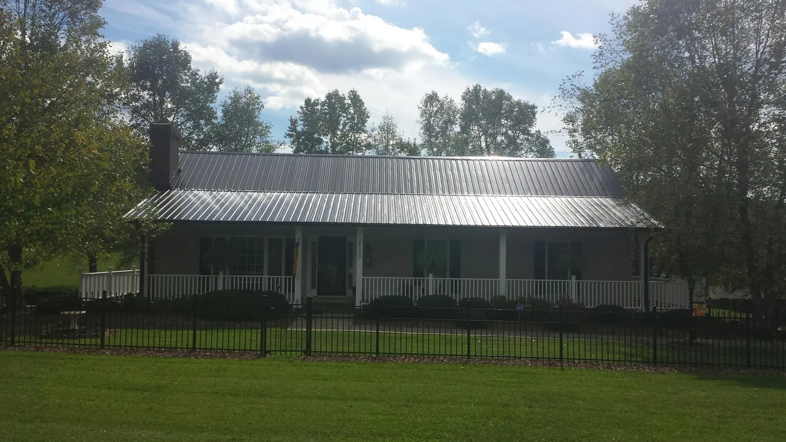 Gray metal roof on a brick ranch with a full width front porch — Gutter Guard Installation work by our crew in Kennedy